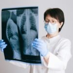 Medical professional in PPE examining chest X-ray results for diagnosis.