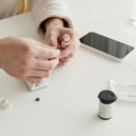 Person preparing insulin injection with medical devices and glucometer on a table.